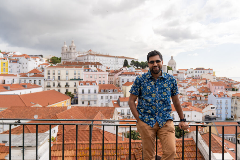 Rohit standing at Miradouro de santa luzia, overlooking the panoramic cityscape of Lisbon