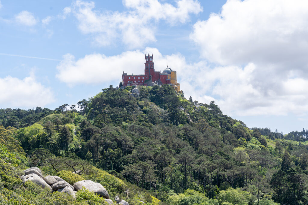 Image of the colorful Pena Palace nestled amidst trees and greenery in Sintra, Portugal