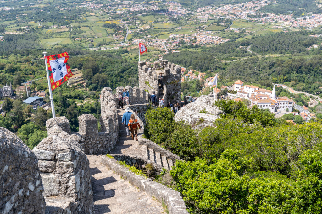 A panoramic view of the Moorish Castle in Lisbon, Portugal, surrounded by lush greenery and overlooking the city below