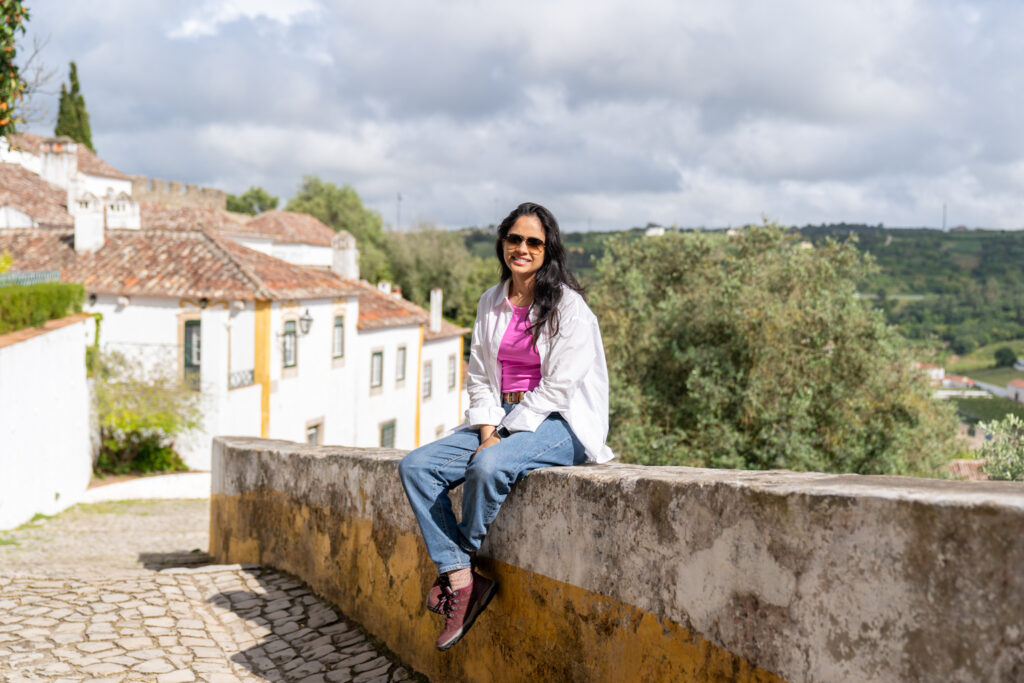 Shivani enjoying the sunshine while exploring the quaint streets of Óbidos, Portugal.