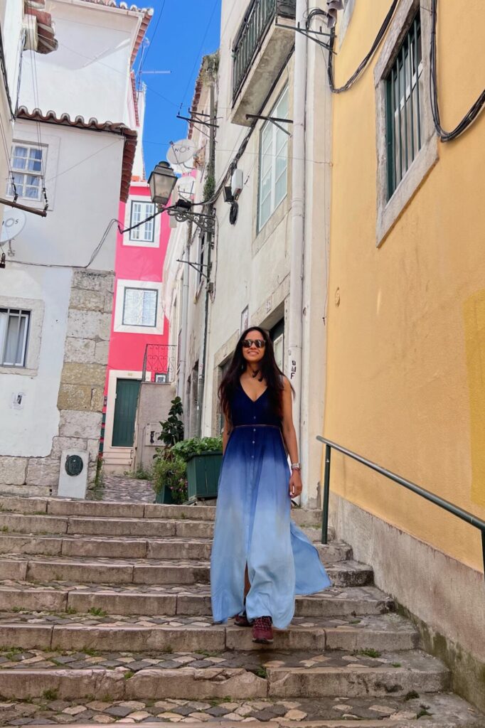 Shivani walking down a set of stairs in the picturesque Alfama neighborhood of Lisbon