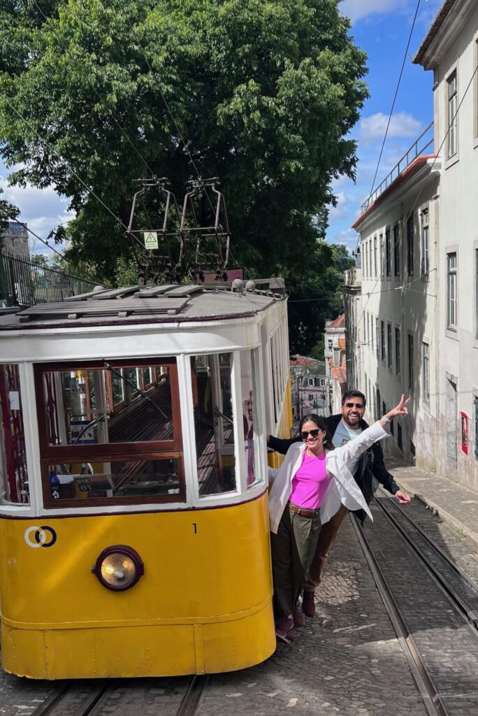 Rohit and Shivani inside a historic Lisbon tram, smiling and enjoying the ride
