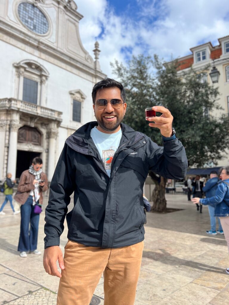 ohit smiling as he enjoys a glass of Ginjinha, a traditional cherry liqueur, in Lisbon