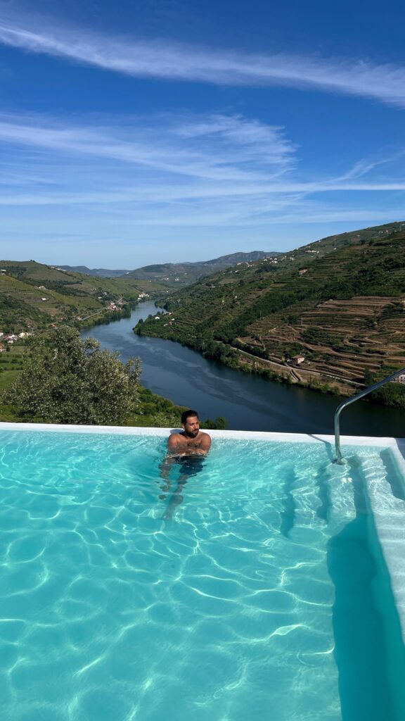 Rohit relaxing in the infinity pool of a picturesque Airbnb villa with panoramic views of the Douro Valley